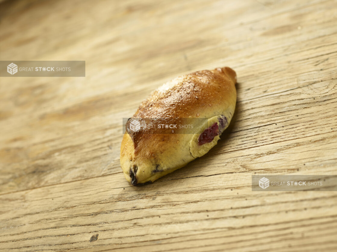 A Blueberry Bun or Shtritzlach - A Sweet Blueberry-Filled Yeast Bun Popular in Jewish Toronto Bakeries - on a Wooden Surface in an Indoor Setting