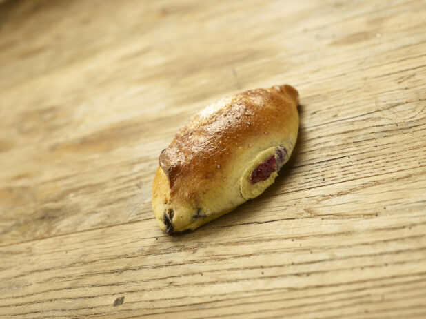 A Blueberry Bun or Shtritzlach - A Sweet Blueberry-Filled Yeast Bun Popular in Jewish Toronto Bakeries - on a Wooden Surface in an Indoor Setting