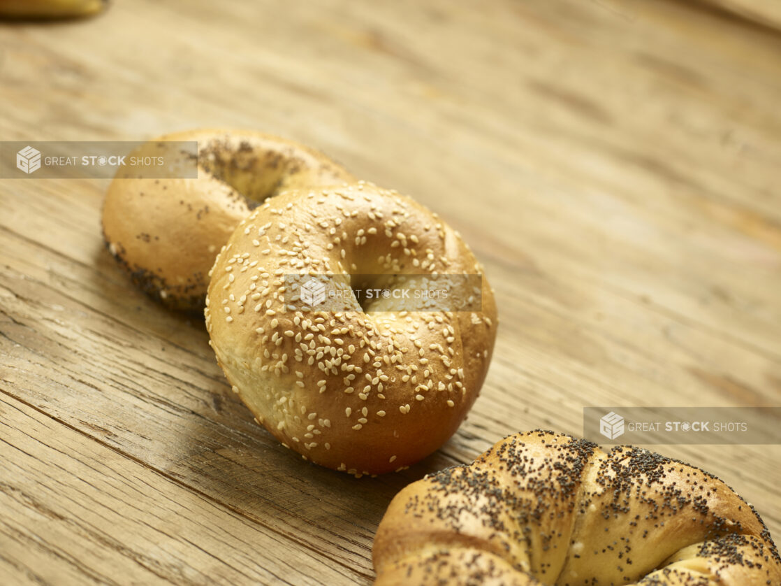 3 assorted whole bagels in a close up view on a wooden background