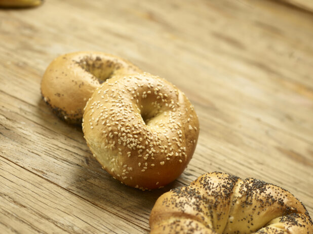 3 assorted whole bagels in a close up view on a wooden background