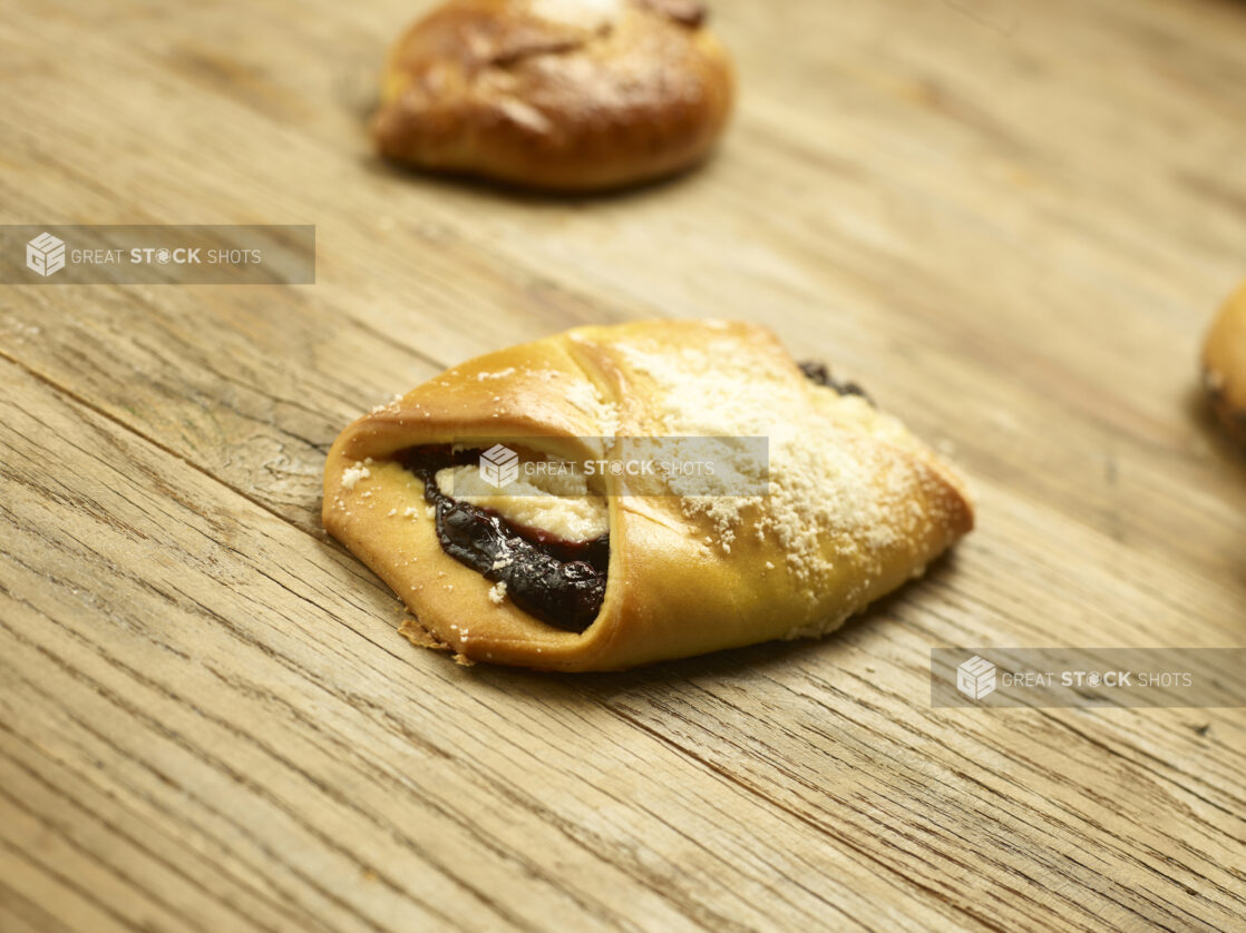 Blueberry cheese danish in a close up view on a wooden background with pastries in the background