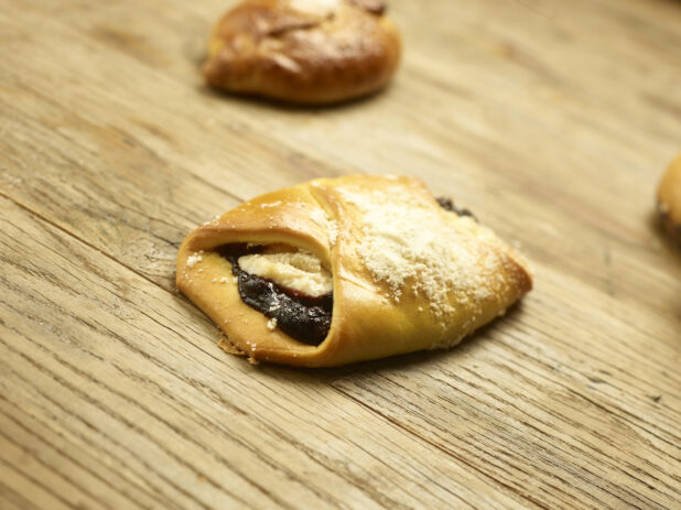 Blueberry cheese danish in a close up view on a wooden background with pastries in the background