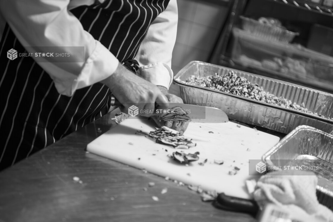 Black and white photo of chef prepping mushrooms in a restaurant kitchen