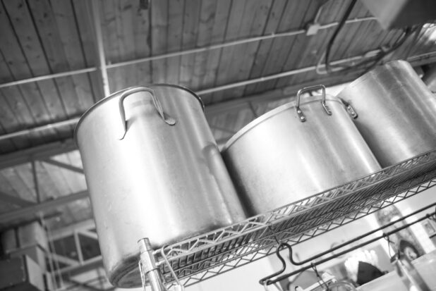 Black and white photo of stock pots in a restaurant kitchen on a metal wire rack