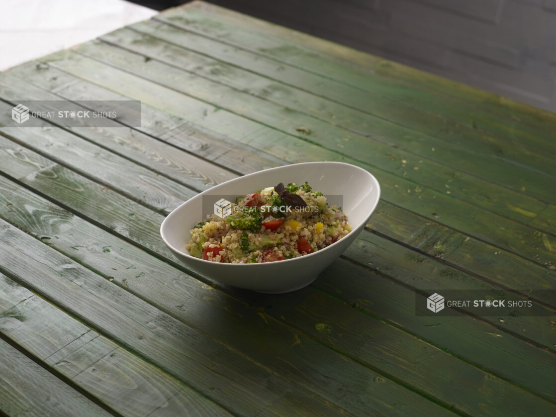 Cous cous salad with fresh vegetables on a hunter green background