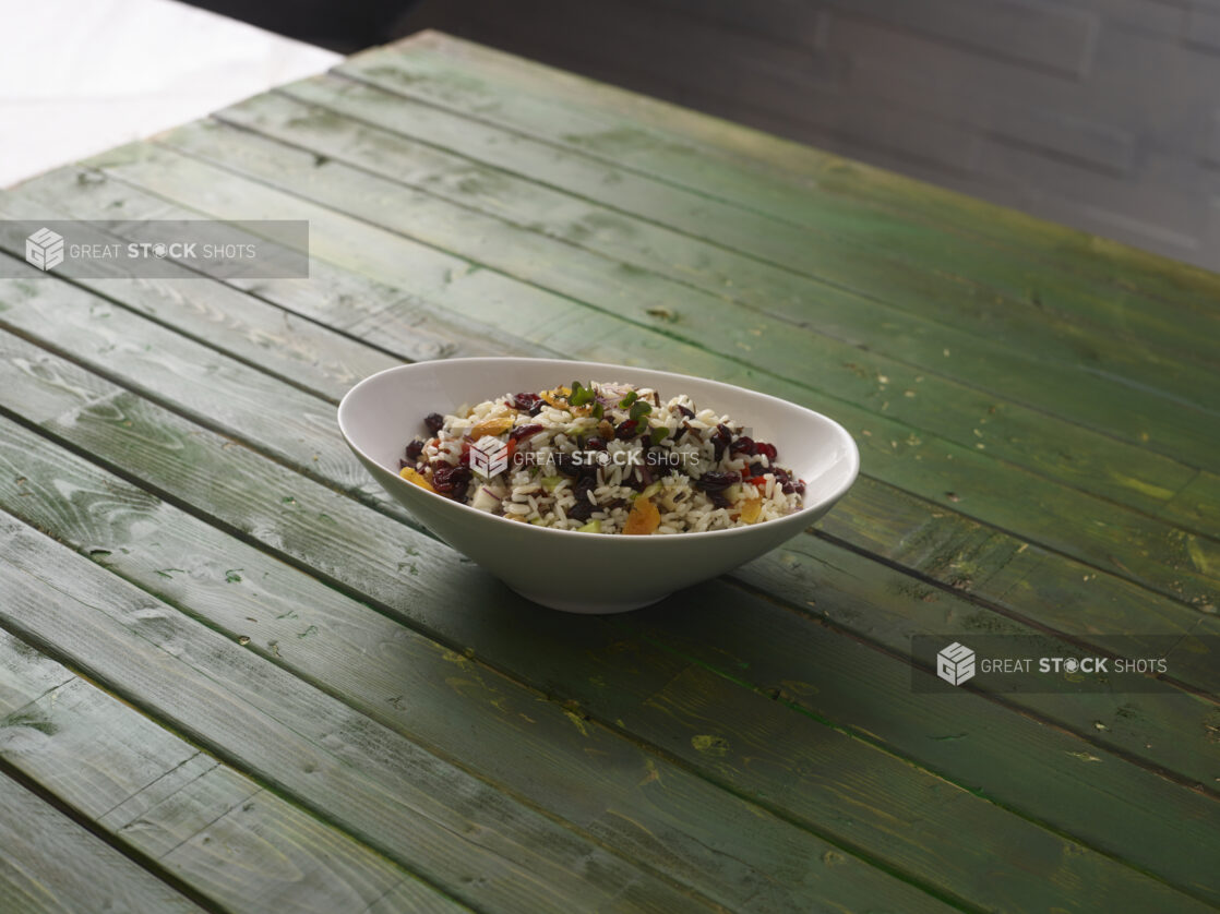 Rice salad with dried cranberries and dried apricots on a hunter green wooden background