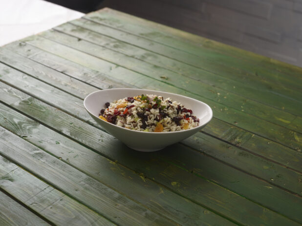 Rice salad with dried cranberries and dried apricots on a hunter green wooden background