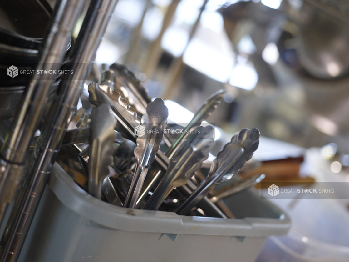 Kitchen utensils in a grey bus pan in a close up view