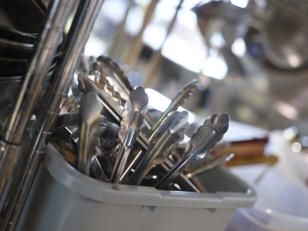 Kitchen utensils in a grey bus pan in a close up view