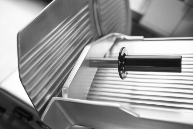 Black and white photo of an industrial meat slicer, close up view