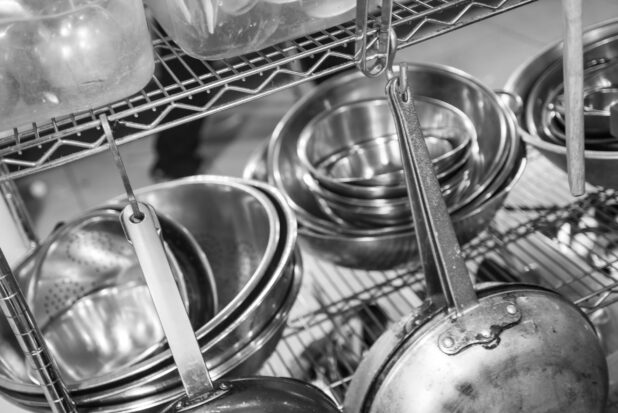Black and white photo of kitchen equipment on a metal wire rack