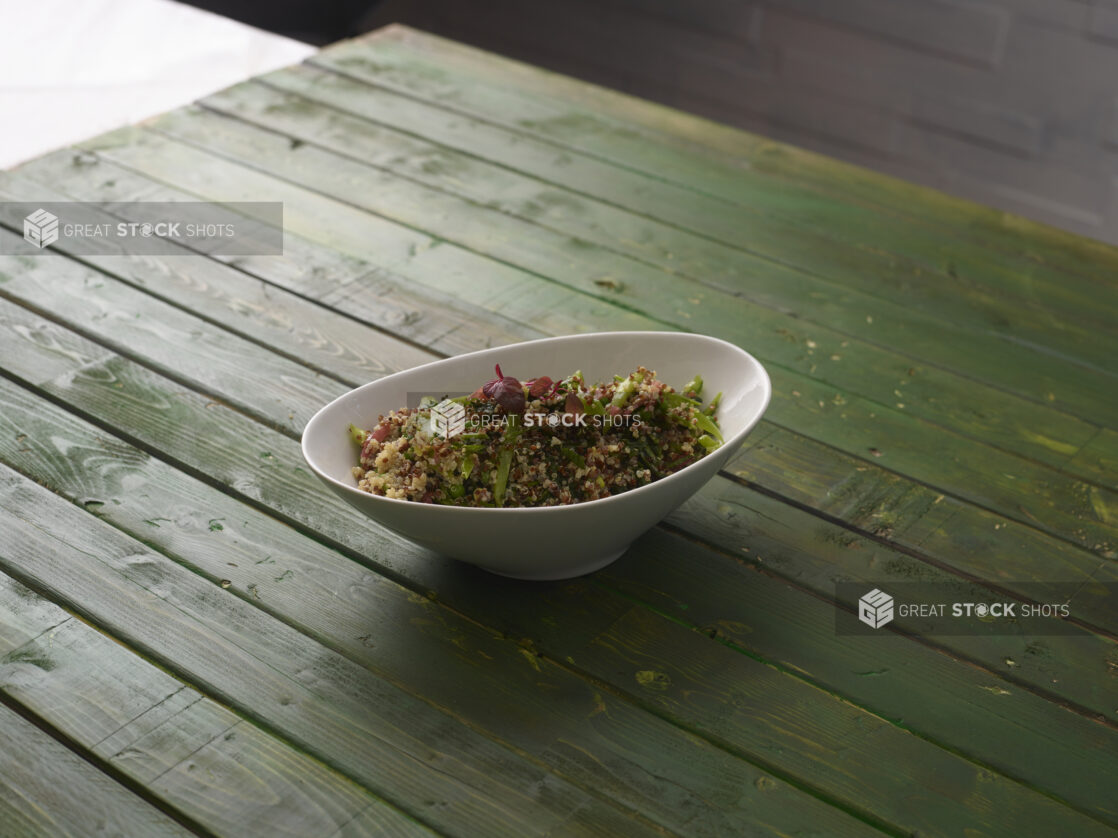 Quinoa salad with fresh vegetables on a hunter green wooden background