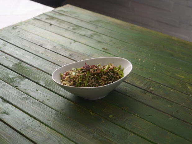 Quinoa salad with fresh vegetables on a hunter green wooden background