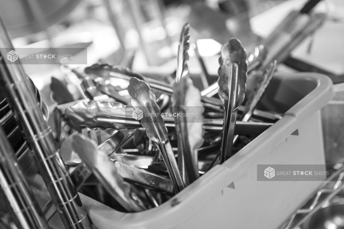 Black and white photo of kitchen utensils and metal wire rack, close up view