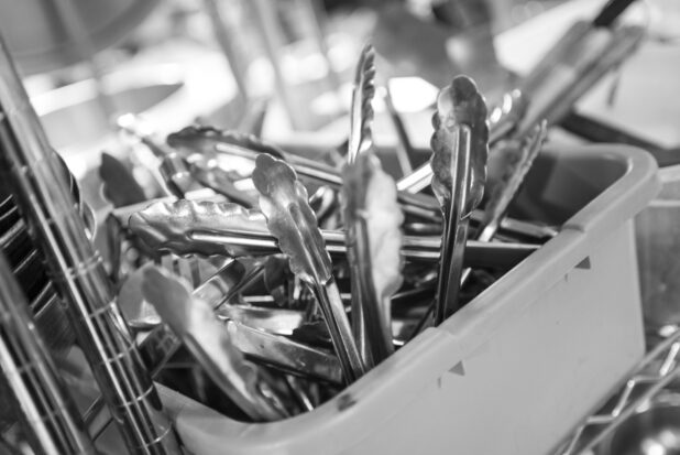 Black and white photo of kitchen utensils and metal wire rack, close up view