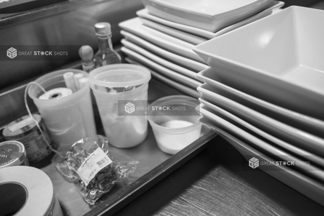 Black and white photo of a restaurant kitchen prep area with white square bowls and cooking accessories