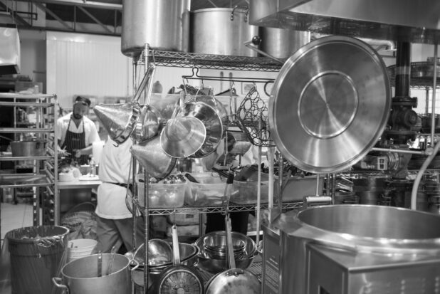 Black and white photo of a restaurant kitchen with equipment and chefs