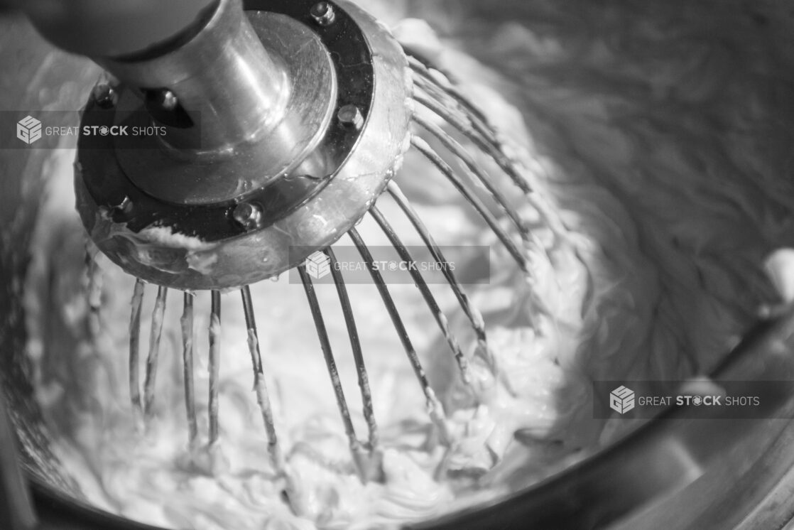 Black and white photo of a mixer making whipped cream, in a close up view