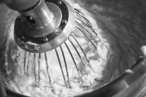 Black and white photo of a mixer making whipped cream, in a close up view