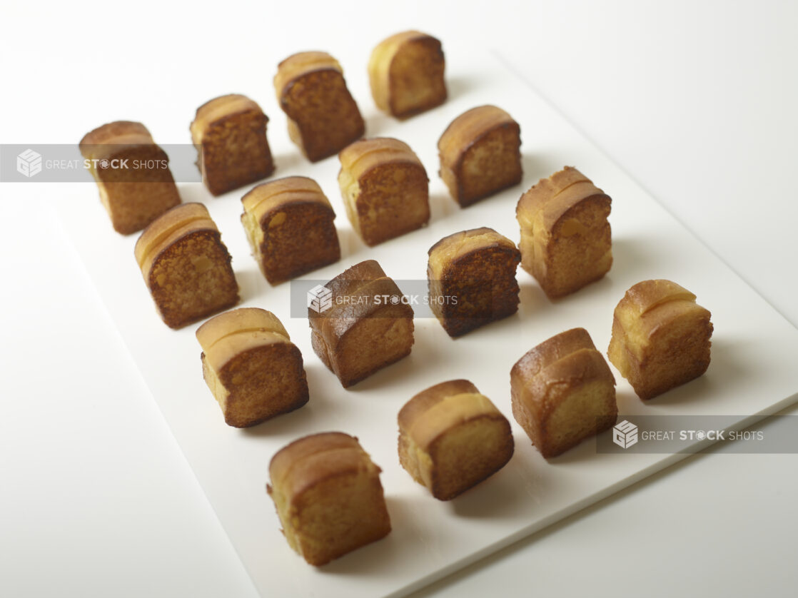 Mini brioche grilled cheese on a rectangular white board, arranged in rows