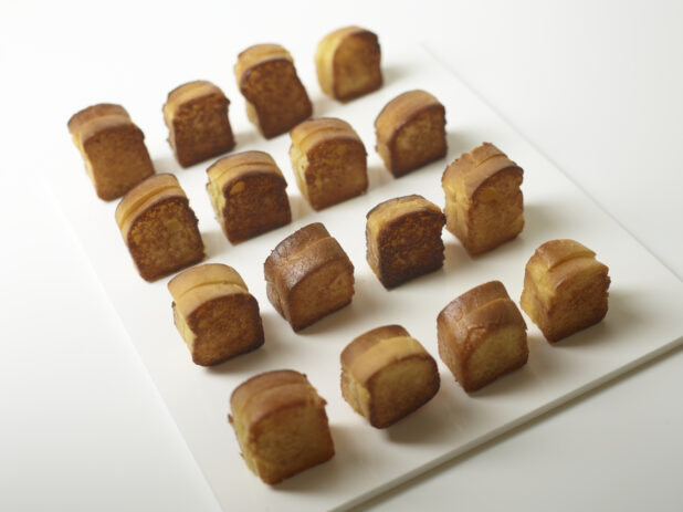 Mini brioche grilled cheese on a rectangular white board, arranged in rows