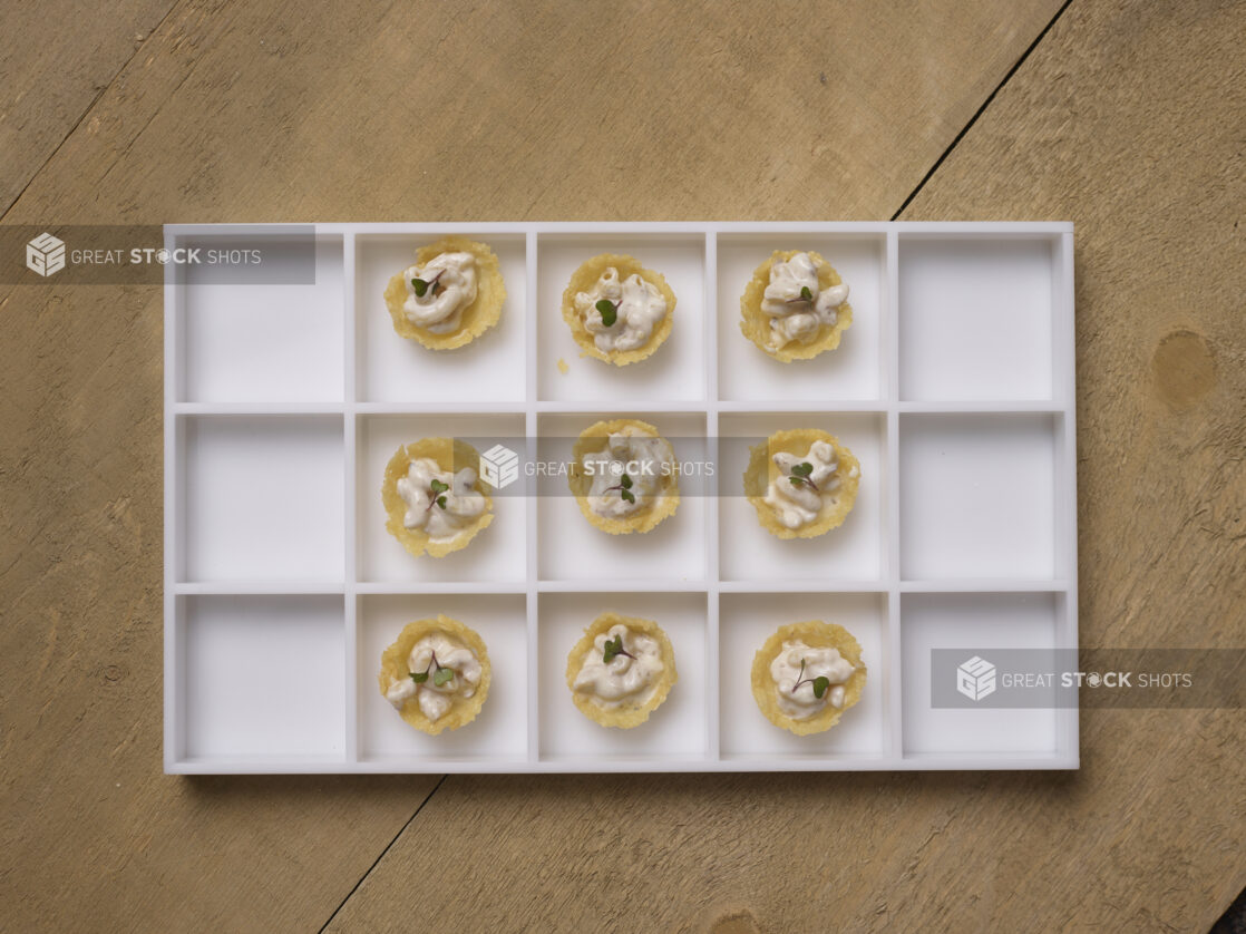 Overhead View of a Platter of White Macaroni and Cheese in a Baked Cheese Cup Passed Appetizer on a Wooden Table