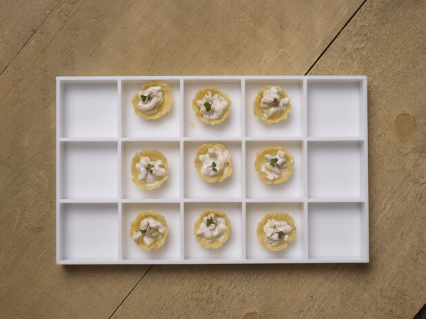 Overhead View of a Platter of White Macaroni and Cheese in a Baked Cheese Cup Passed Appetizer on a Wooden Table