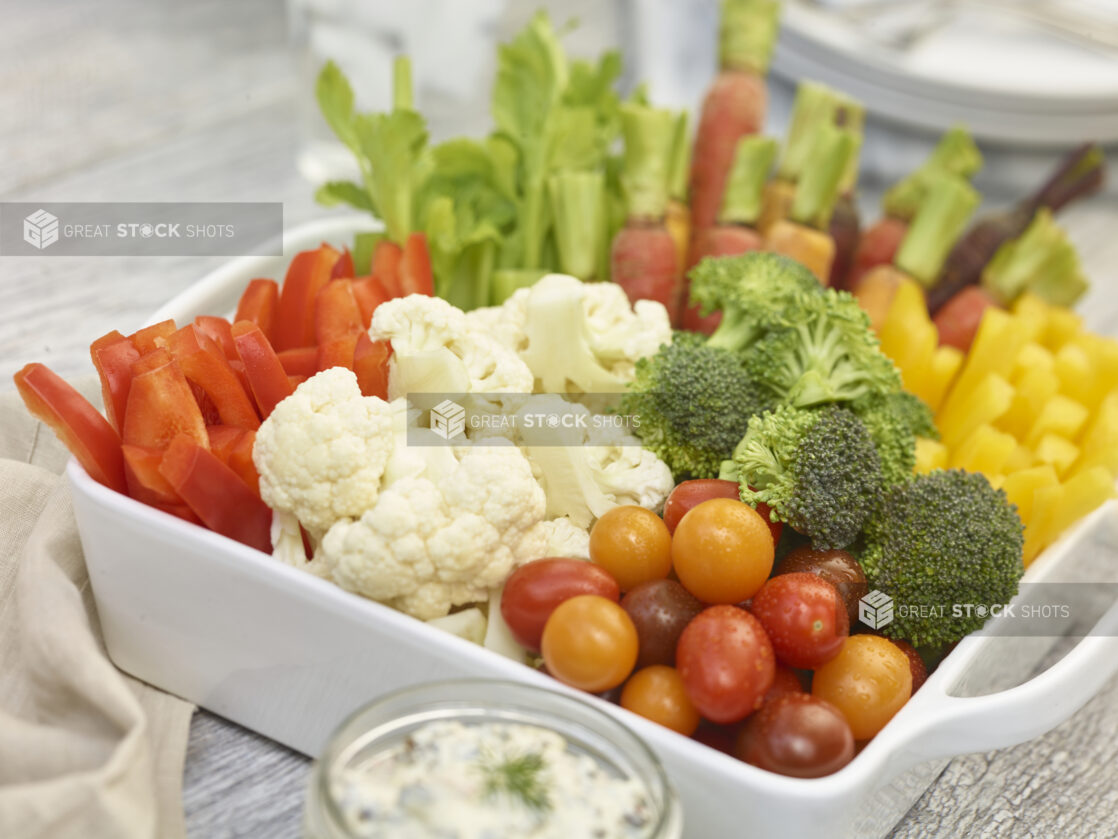 Assorted Crudites/veggie platter in a white square ceramic dish with dip in a mason jar, close up view