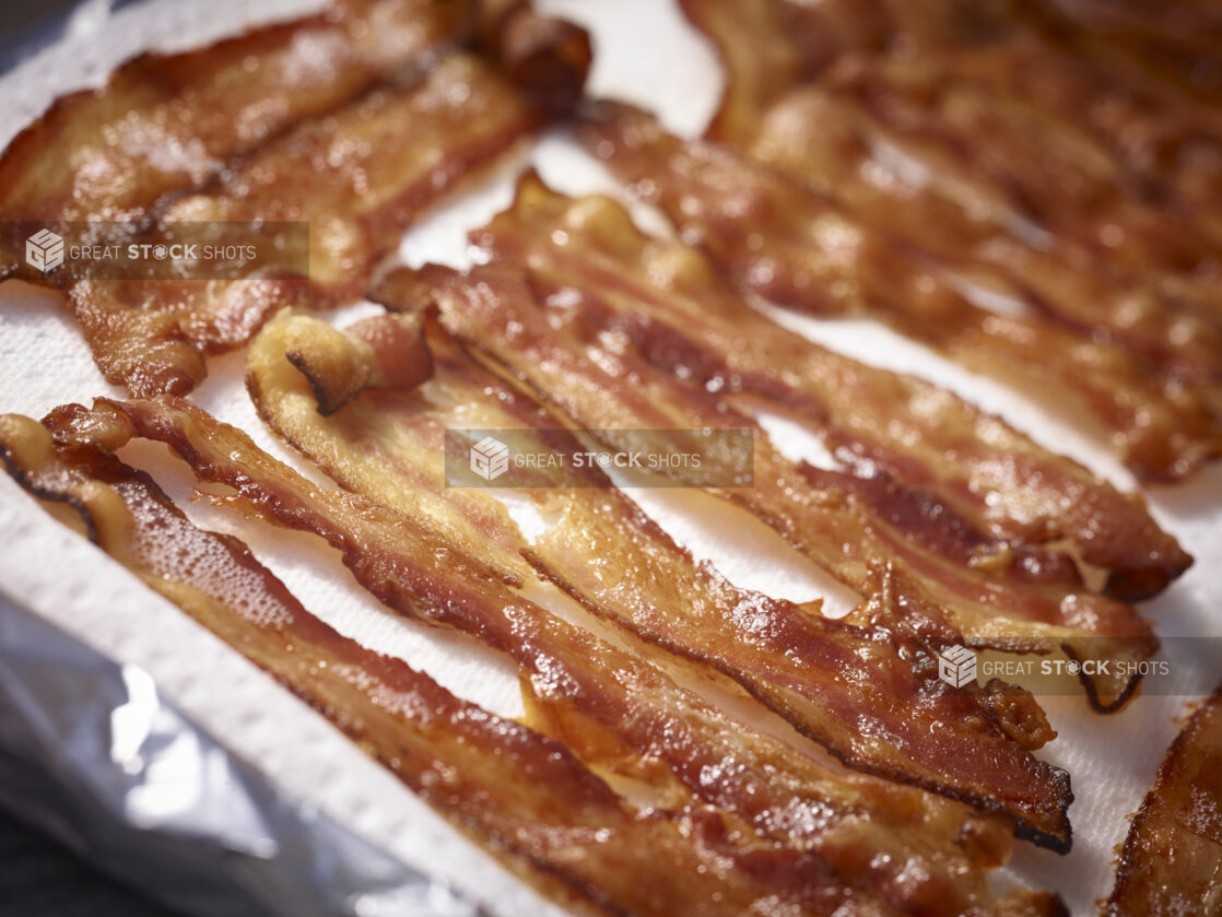 Slices of crispy cooked bacon on a white background in a close up 45 degree angle view