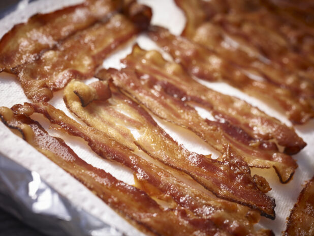 Slices of crispy cooked bacon on a white background in a close up 45 degree angle view