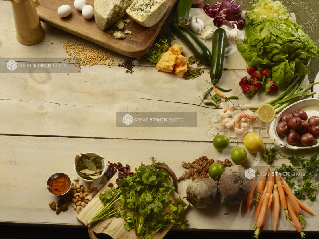 Various fresh vegetables, herbs, fruit, nuts, eggs and cheese with cooked shrimp arranged on wooden boards, in a beautiful display