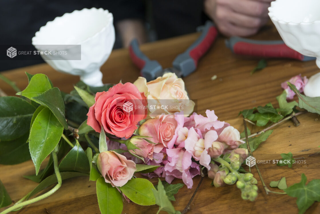 Arrangement of roses and snapdragons being prepared on a florist's work table