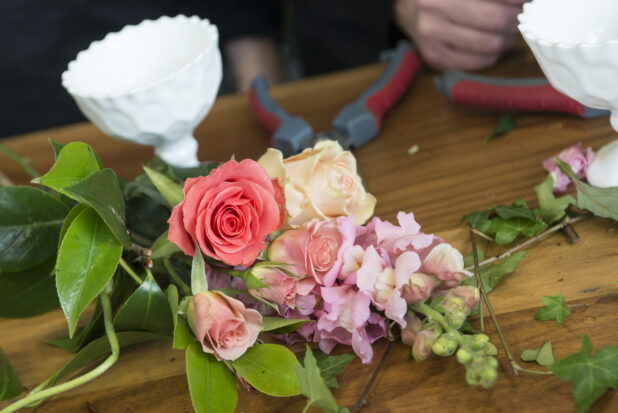 Arrangement of roses and snapdragons being prepared on a florist's work table