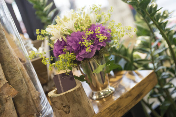 Floral arrangement with white freesia and purple carnations in a silver vase in a flower shop setting