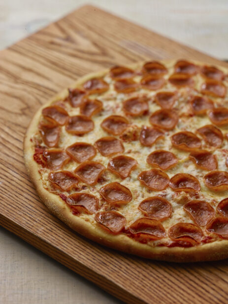 Whole pepperoni pizza in a close up view on a wooden board