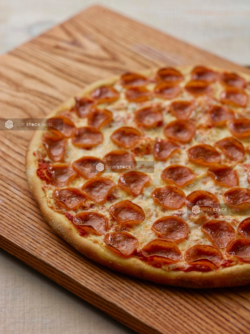 Whole pepperoni pizza in a close up view on a wooden board