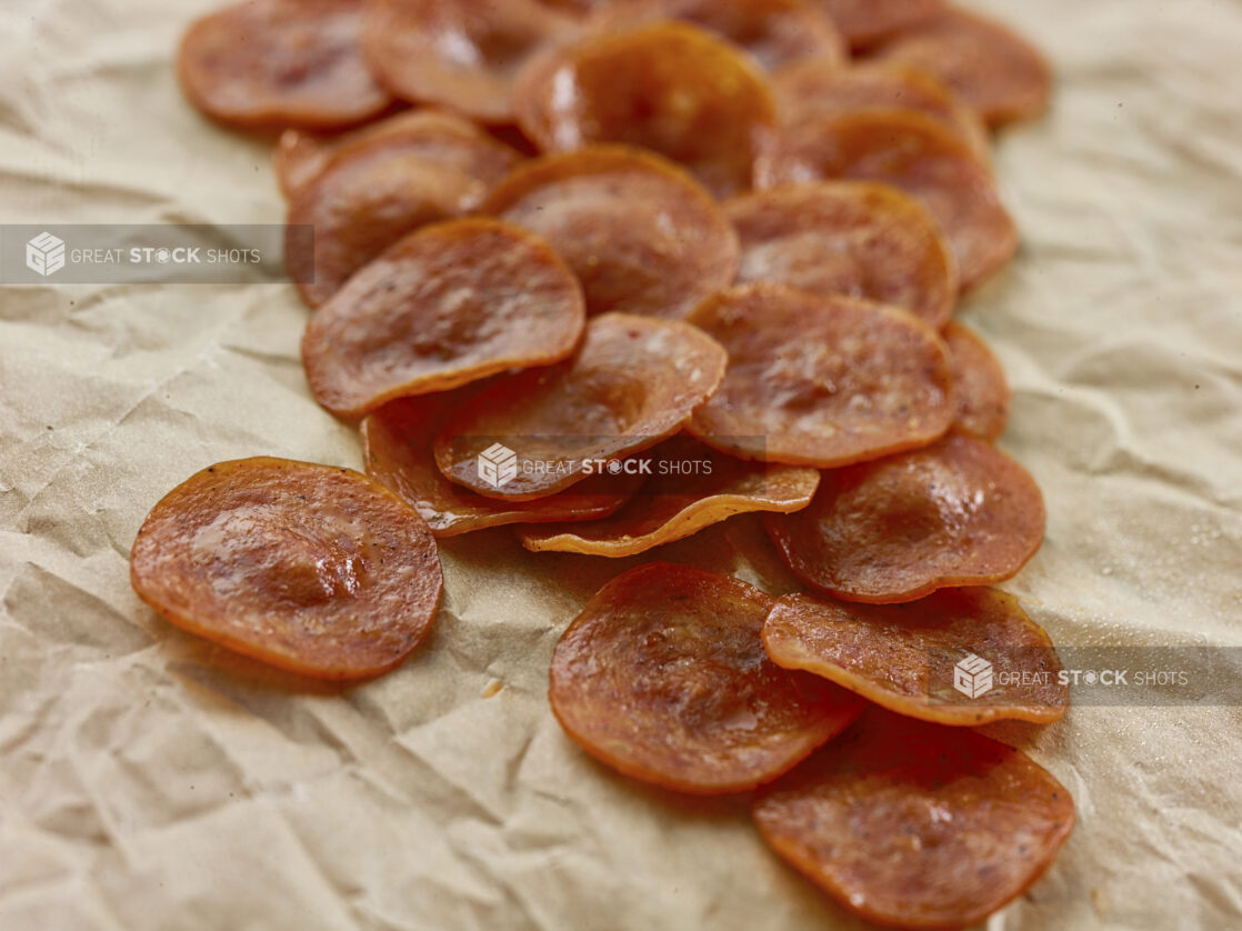 Slices of pepperoni in a close up view on parchment paper