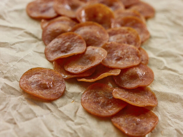 Slices of pepperoni in a close up view on parchment paper