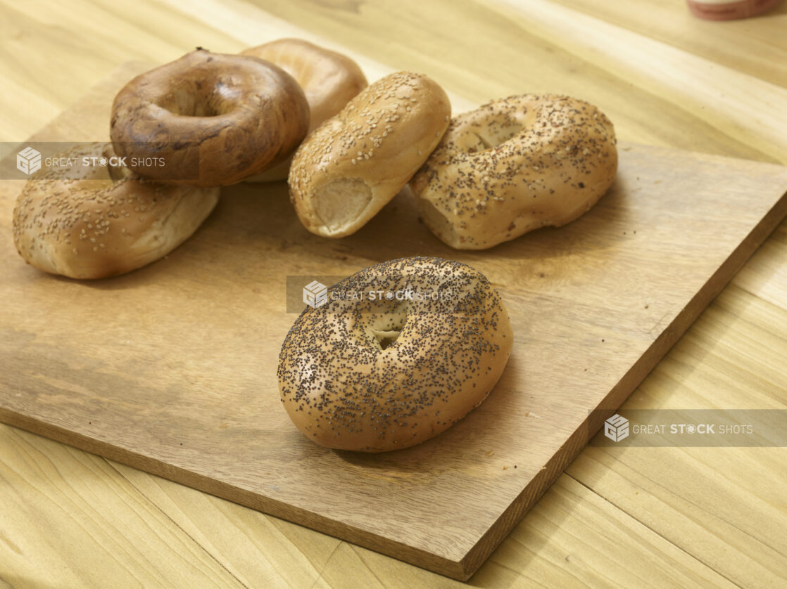 Assorted whole bagels on a wooden board