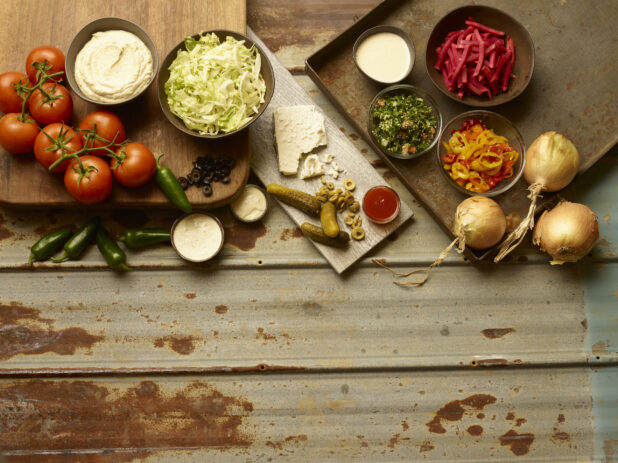 Middle Eastern salad ingredients arranged on wooden boards all on a rustic tin background