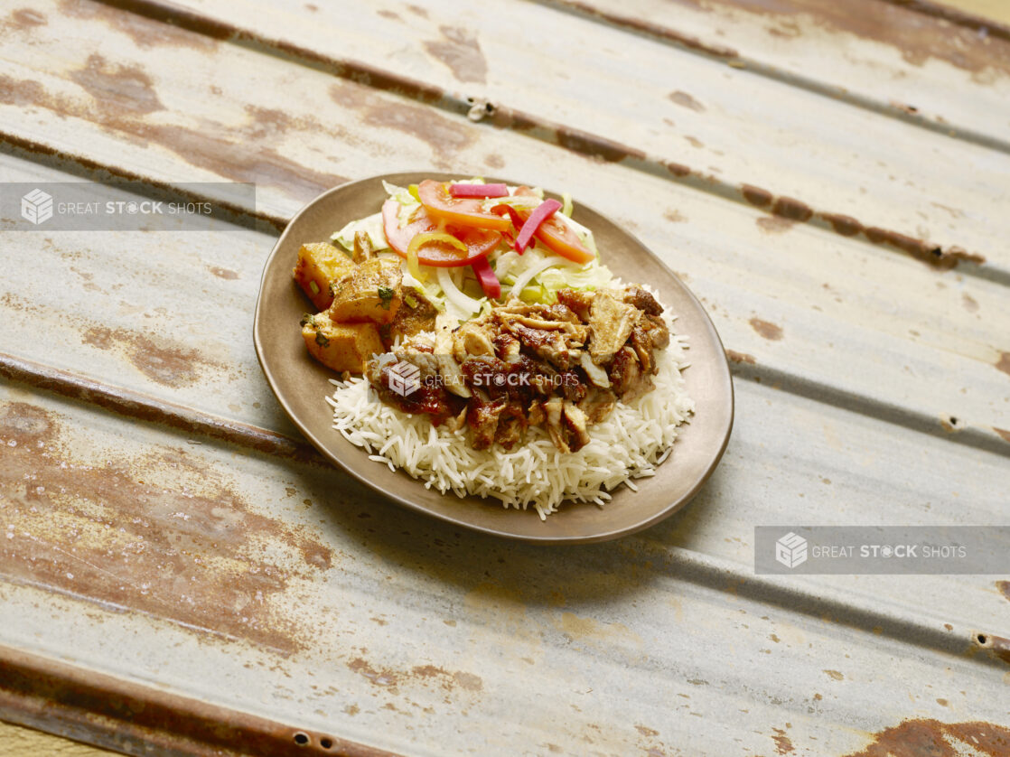 Chicken shawarma dinner on a round ceramic plate on a rustic tin background