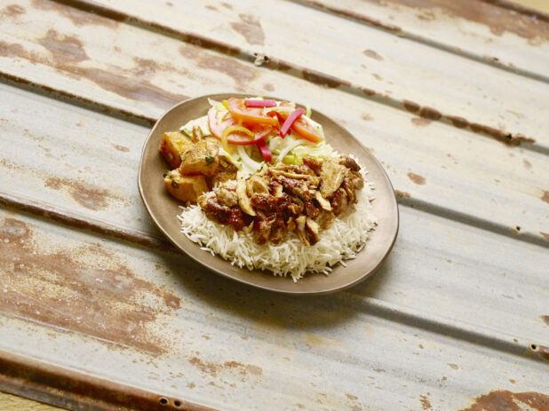 Chicken shawarma dinner on a round ceramic plate on a rustic tin background