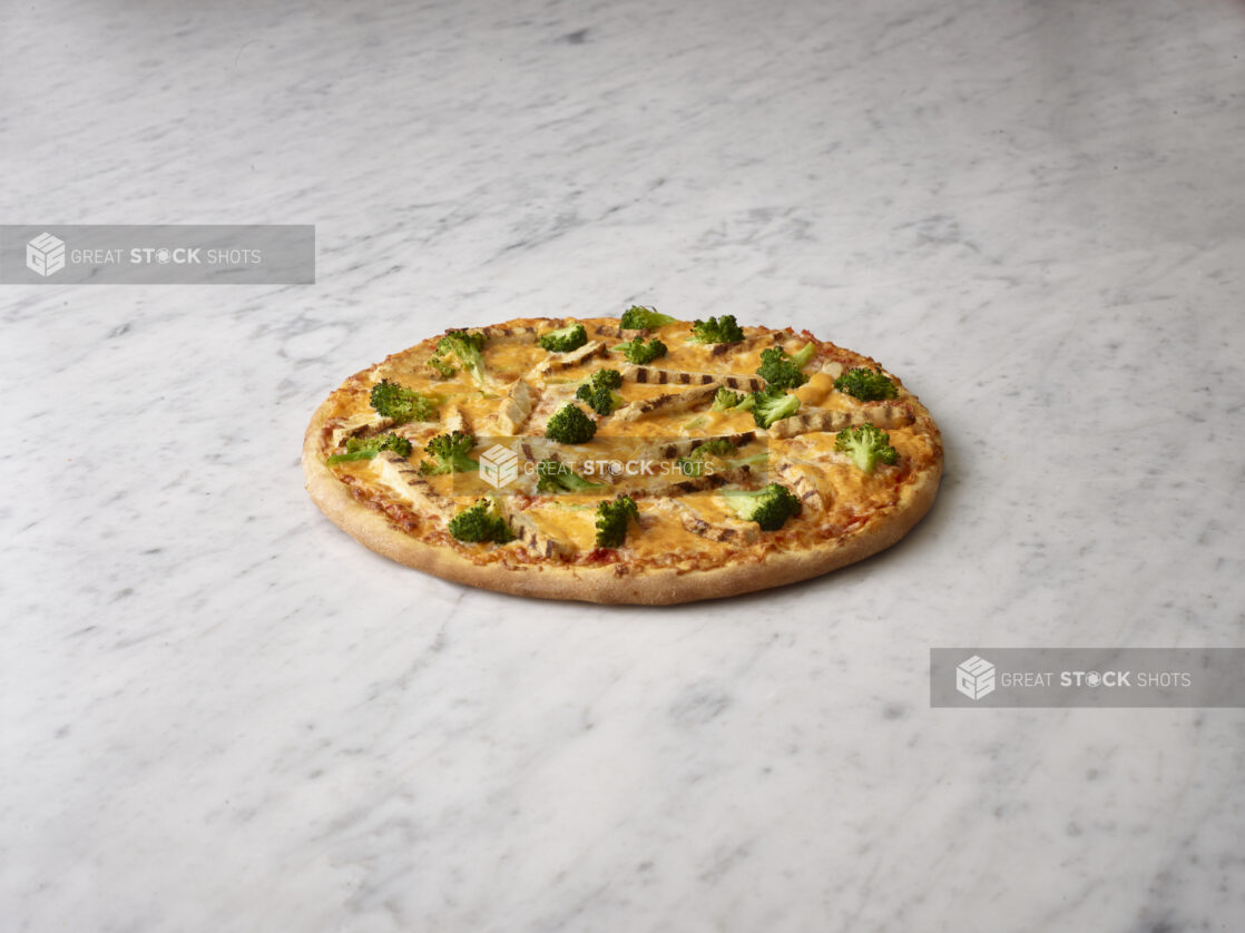 Whole chicken and broccoli pizza on a white marble background