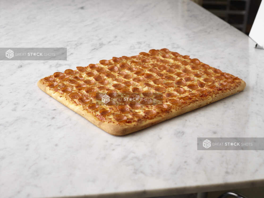 Party size pepperoni pizza on a white marble background