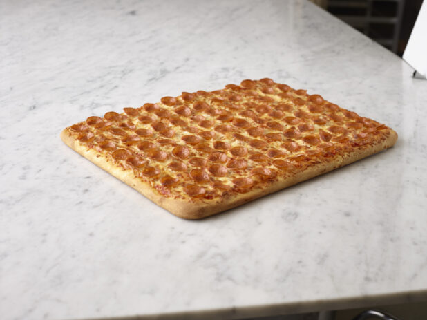 Party size pepperoni pizza on a white marble background