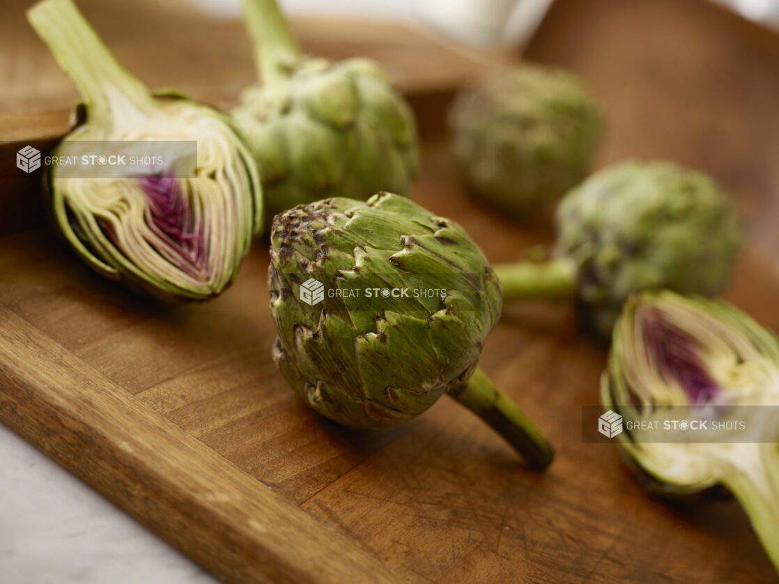 Fresh whole and sliced artichoke on a wooden board on a 45 degree angle