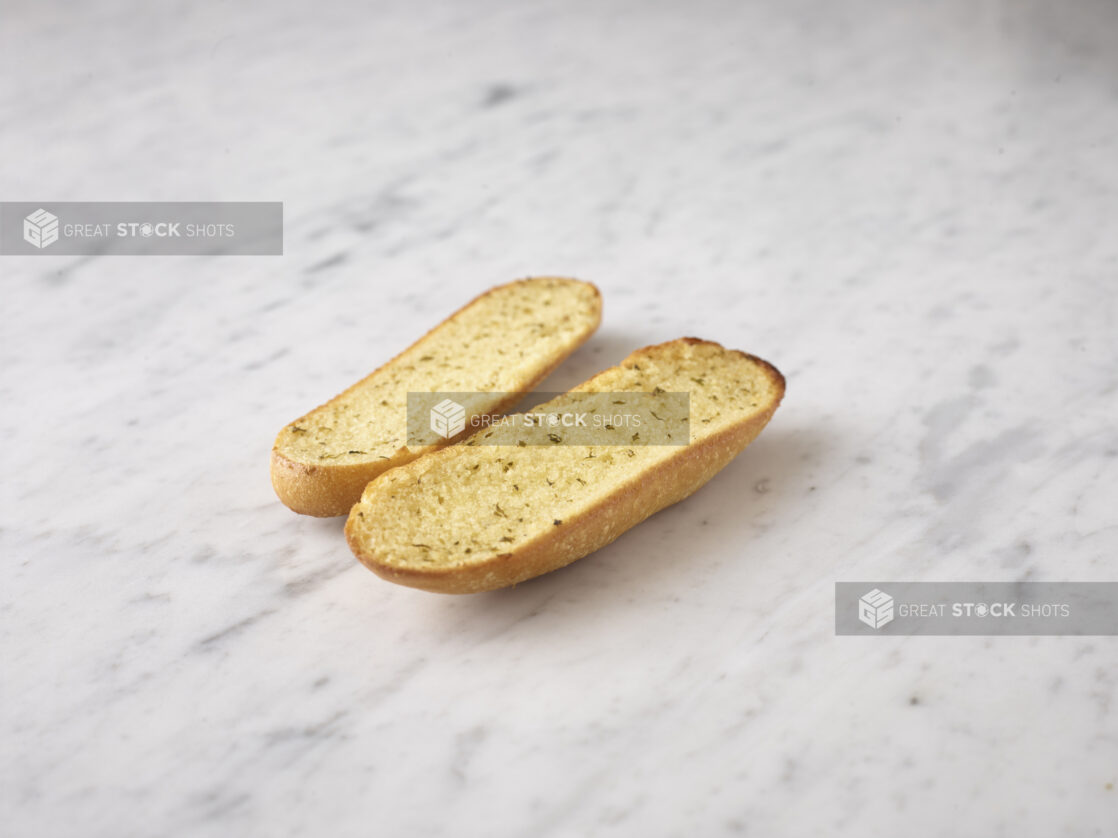 Whole garlic bread on a white marble background