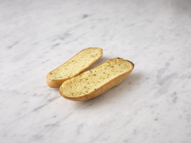 Whole garlic bread on a white marble background