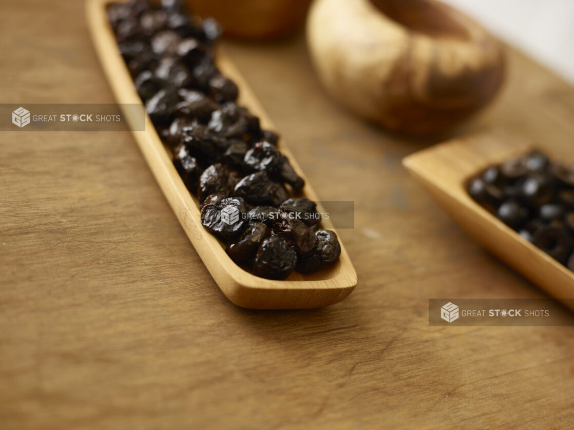 Whole pitted dates in a wooden rectangular platter on a rustic wooden background