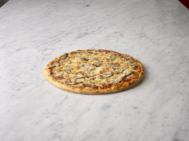 Whole portobello mushroom pizza on a white marble background
